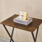 Rustic folding TV tray table with a clock and books, perfect for maximizing space.