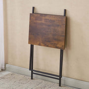 Rustic folding TV tray table stored flat against the wall, showcasing its compact design and wooden finish.
